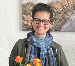 Rabea Wienholt hält lächelnd einen Blumenstrauß mit orangenen Rosen.