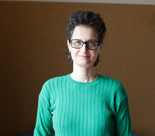 Rabea Wienholt in einem grünen, gerippten Pullover vor einem schlichten braunen Hintergrund.
